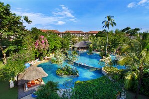 Et resort med flere swimmingpools omgivet af frodig vegetation og palmer.