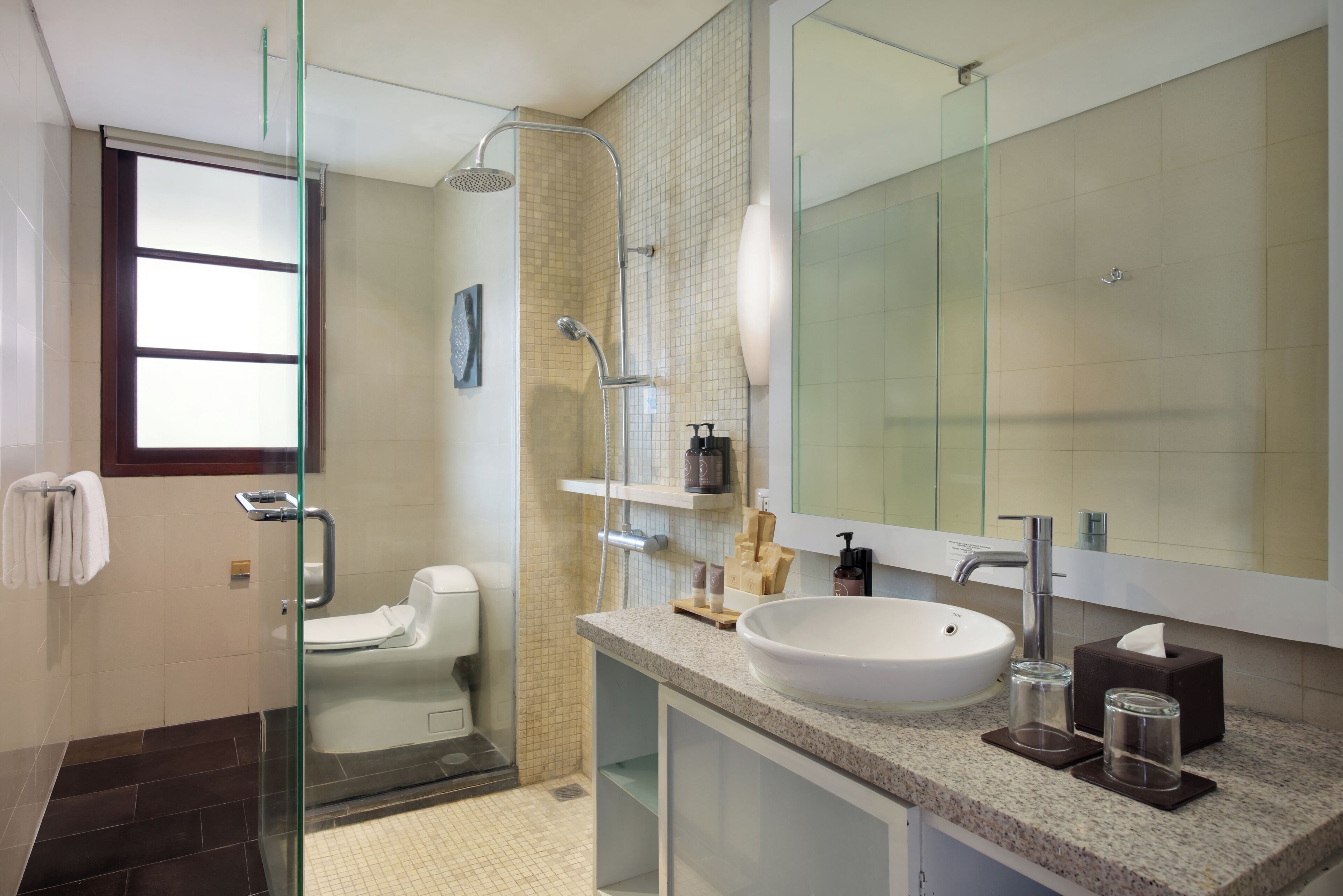 A modern bathroom with a glass shower enclosure, a white sink, and a large mirror.