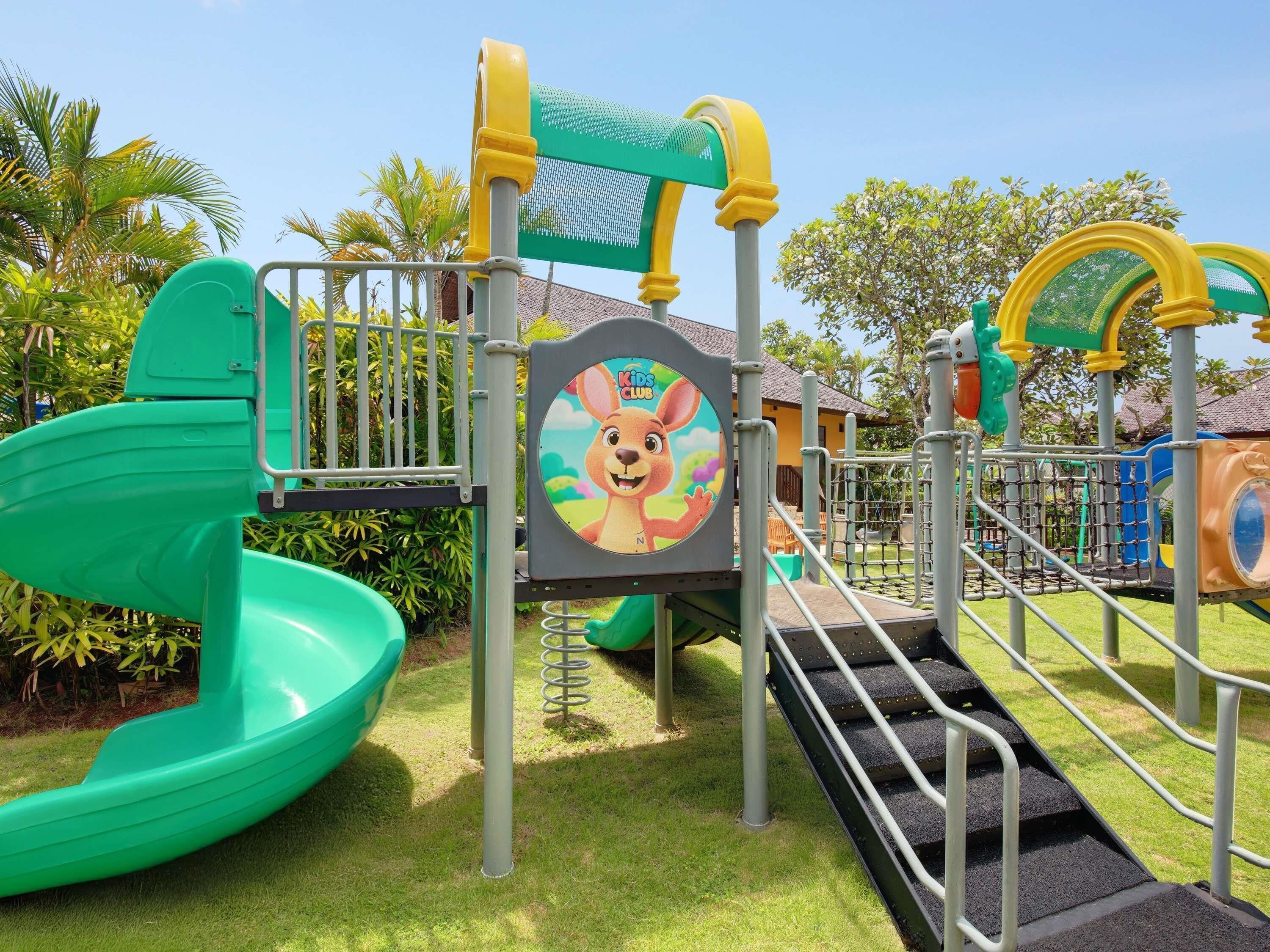 A children's play area with a slide, climbing structures, and a safety sign.