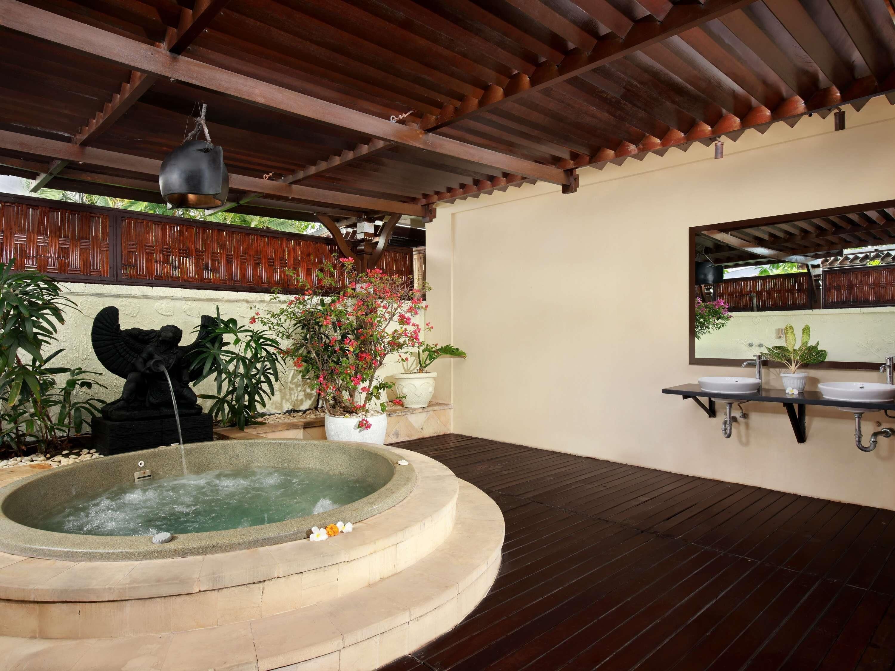 A spa area with a hot tub, a statue, and potted plants.