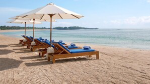 A beach with sun loungers and umbrellas, a clear sky, and a calm sea. - Novotel Bali Nusa Dua (Nusa Dua)
