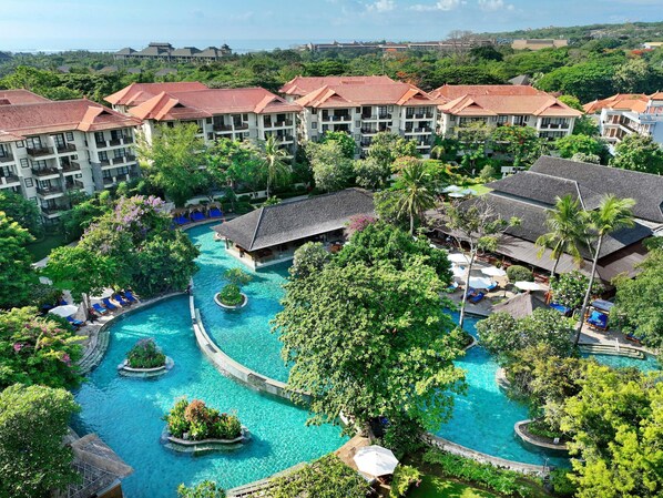 Et resort med flere bygninger, en central swimmingpool og frodig vegetation.