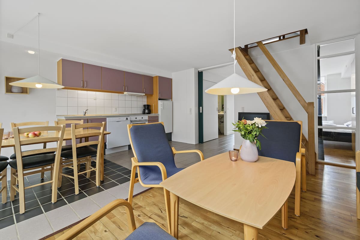 Een moderne keuken met houten kastjes, een eettafel met stoelen en een trap.