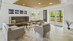 A spacious living area with a large sofa, two armchairs, a coffee table, and a wooden ceiling. - Ribe Byferie Resort (Ribe)