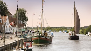 A harbor with boats docked, a pier with people, and buildings in the background. - Ribe Byferie Resort (Ribe)