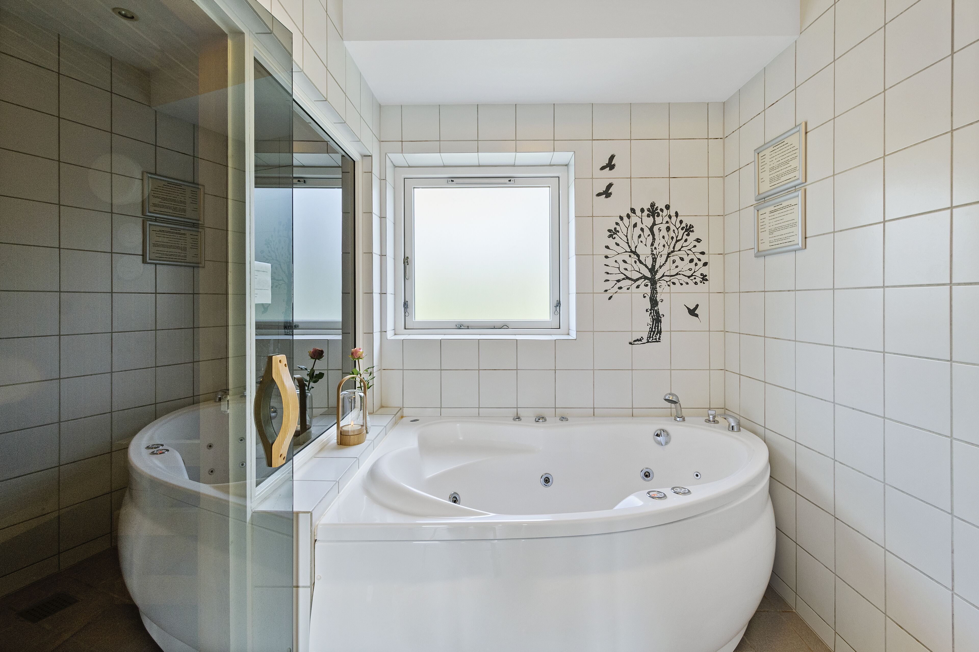 Une salle de bain moderne dotée d’une grande baignoire îlot, d’une douche à parois de verre et d’une fenêtre laissant entrer la lumière naturelle.