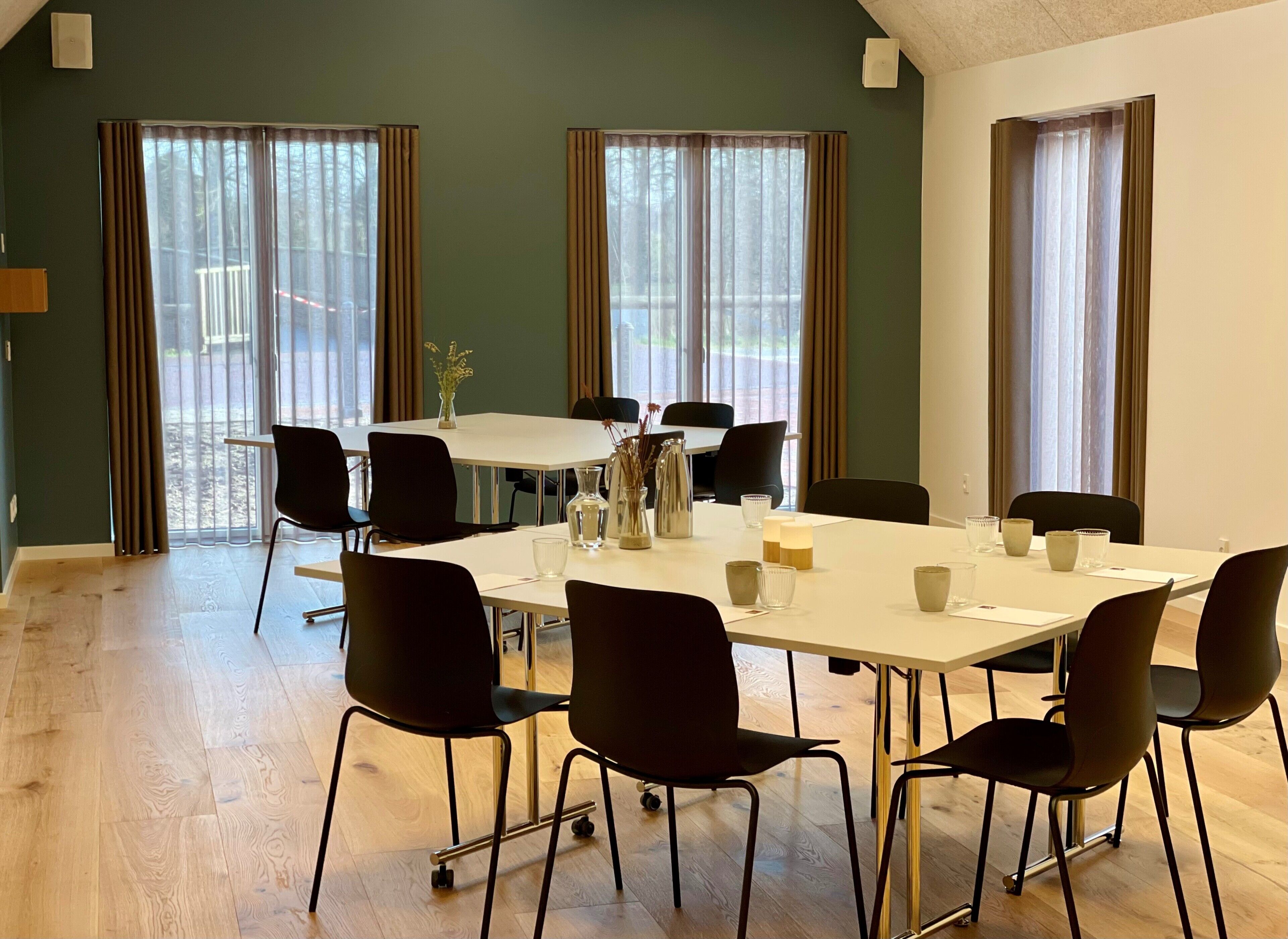 A conference room with a large table, chairs, and a vase of flowers.