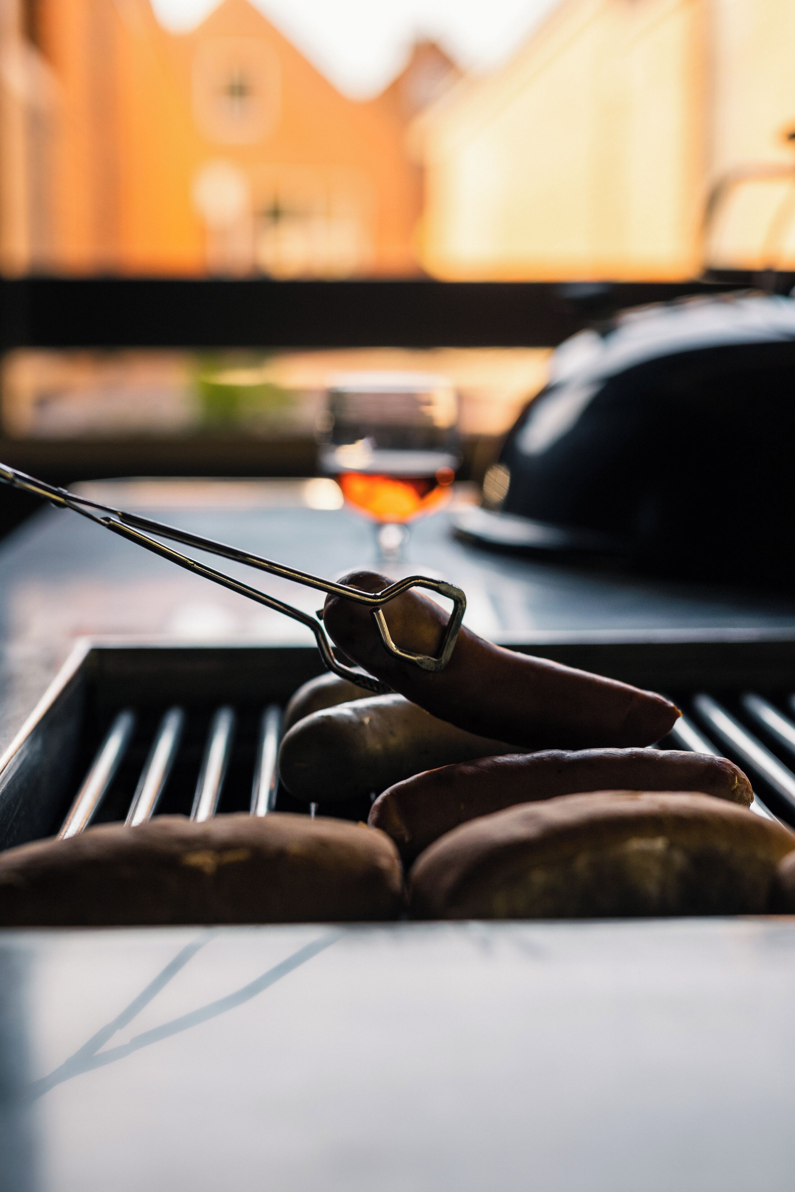 A grill with sausages and a glass of red wine.