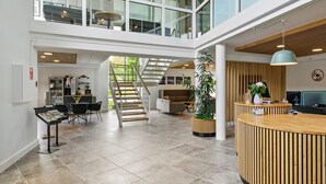 A spacious lobby with a reception desk, seating area, staircase, and a view of the upper floor. - Ribe Byferie Resort (Ribe)