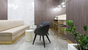 Un interior moderno con un sofá, sillas, una zona de comedor y una planta.