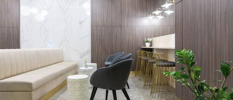A modern interior with a sofa, chairs, a dining area, and a plant.