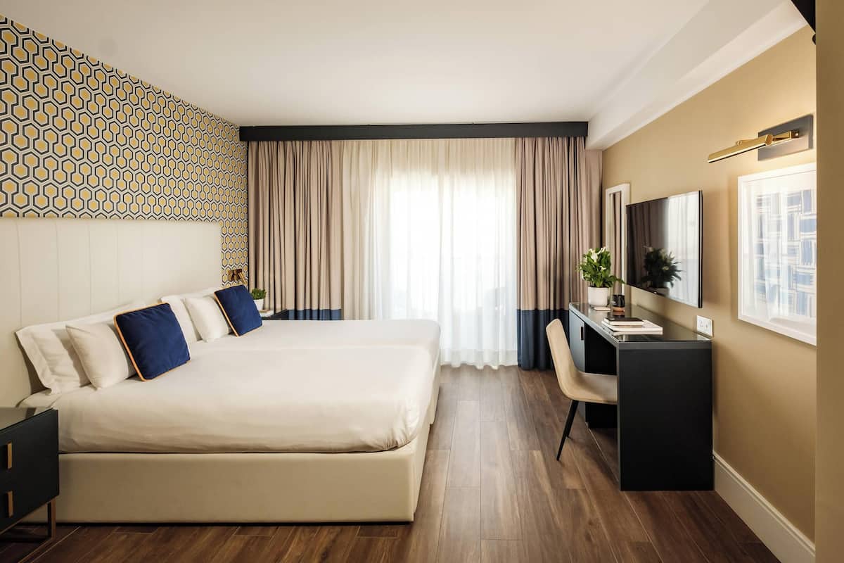 A modern hotel room with a large bed, a desk, and a television.