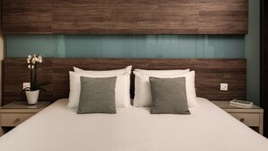 Una habitación de hotel con una cama grande, dos mesitas de noche, una planta en maceta y un cabecero de madera.