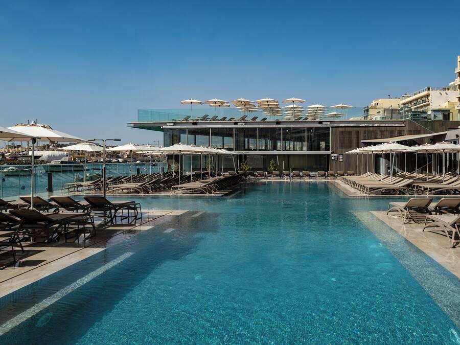 Una piscina techada, una piscina al aire libre, sombrillas