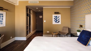 Una camera d'albergo con un letto grande, una sedia, un tavolino e un armadio.