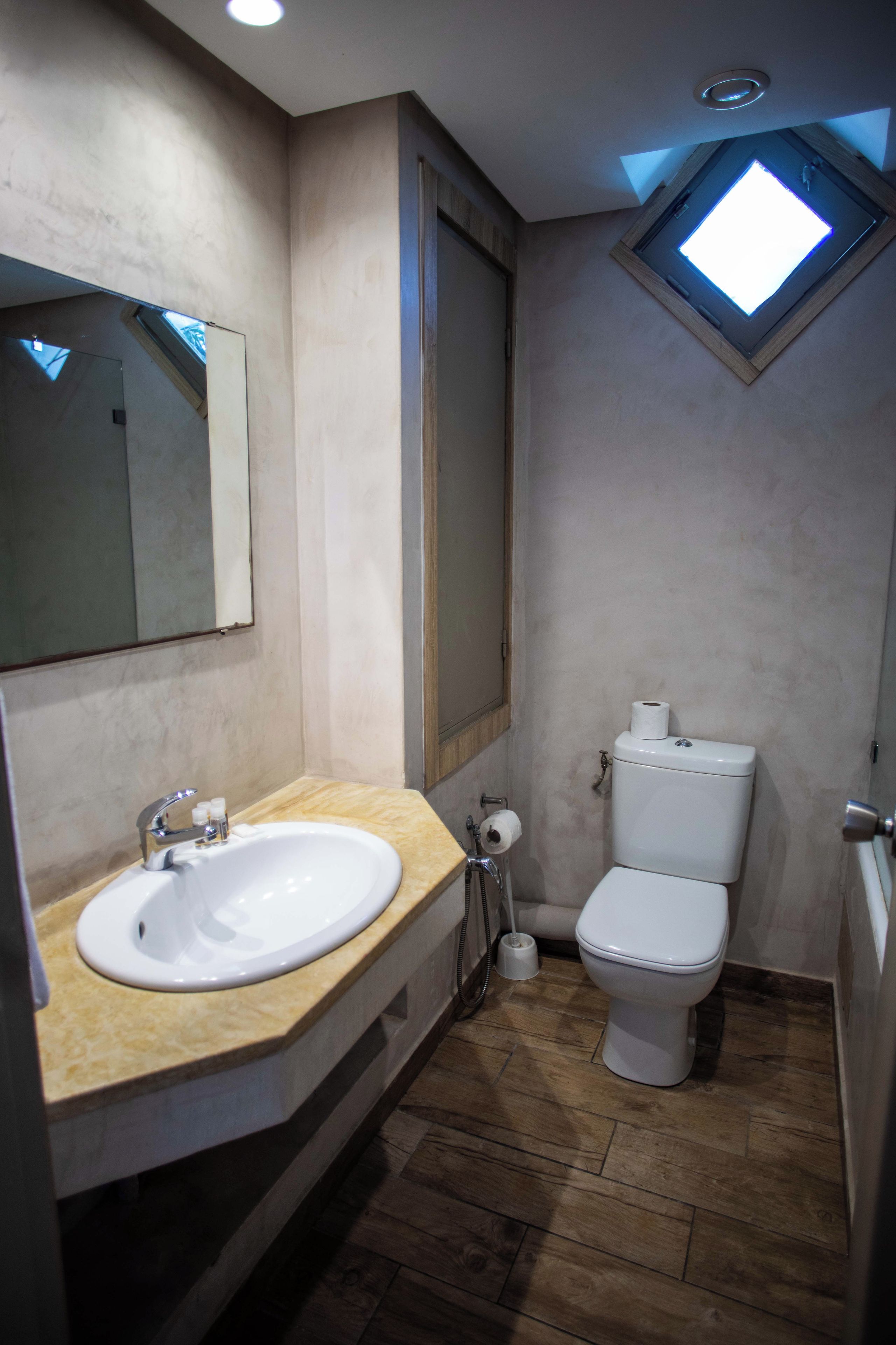 Un baño con lavamanos, inodoro y tragaluz.