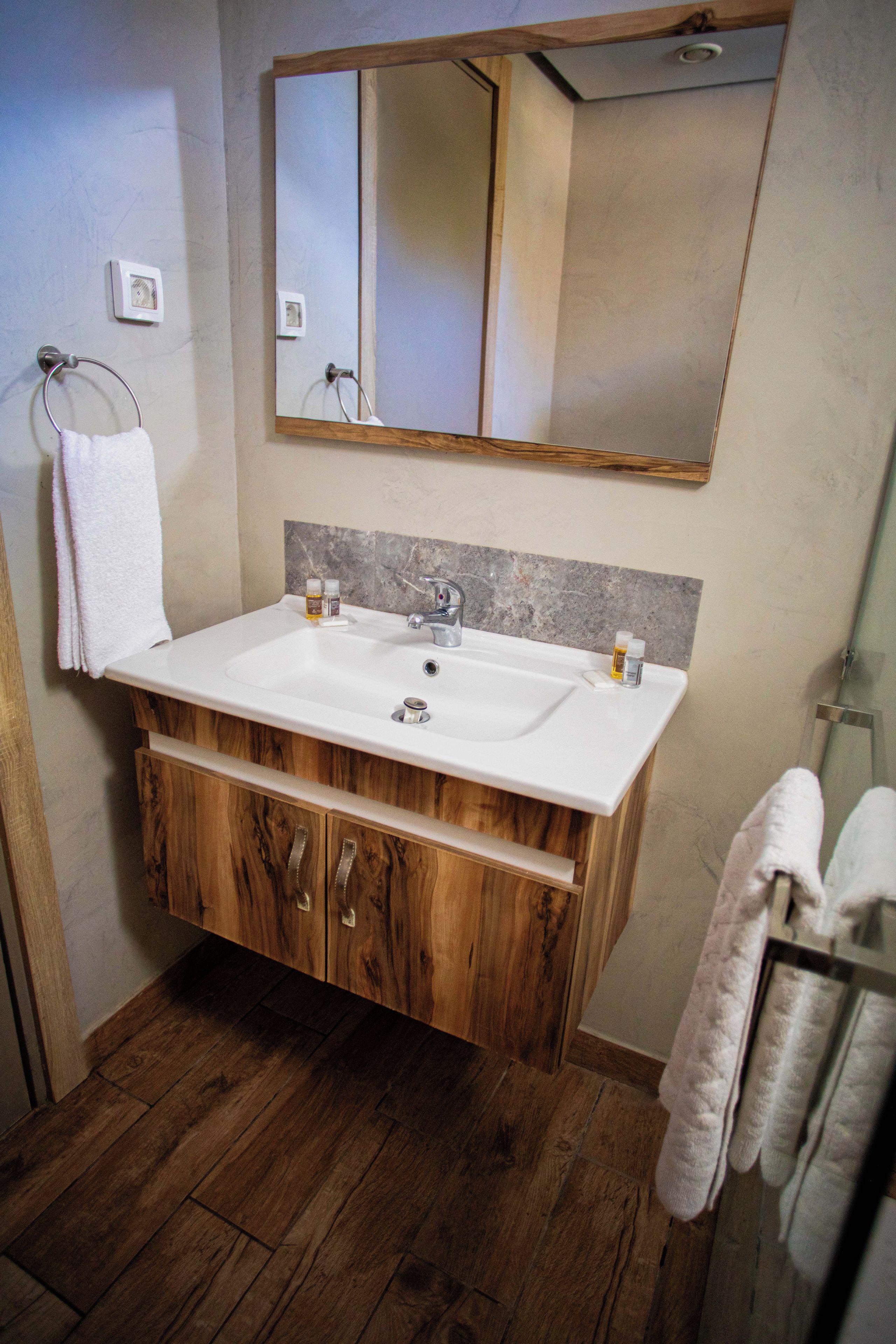 Une salle de bain avec un meuble-lavabo en bois, un lavabo blanc et un grand miroir.
