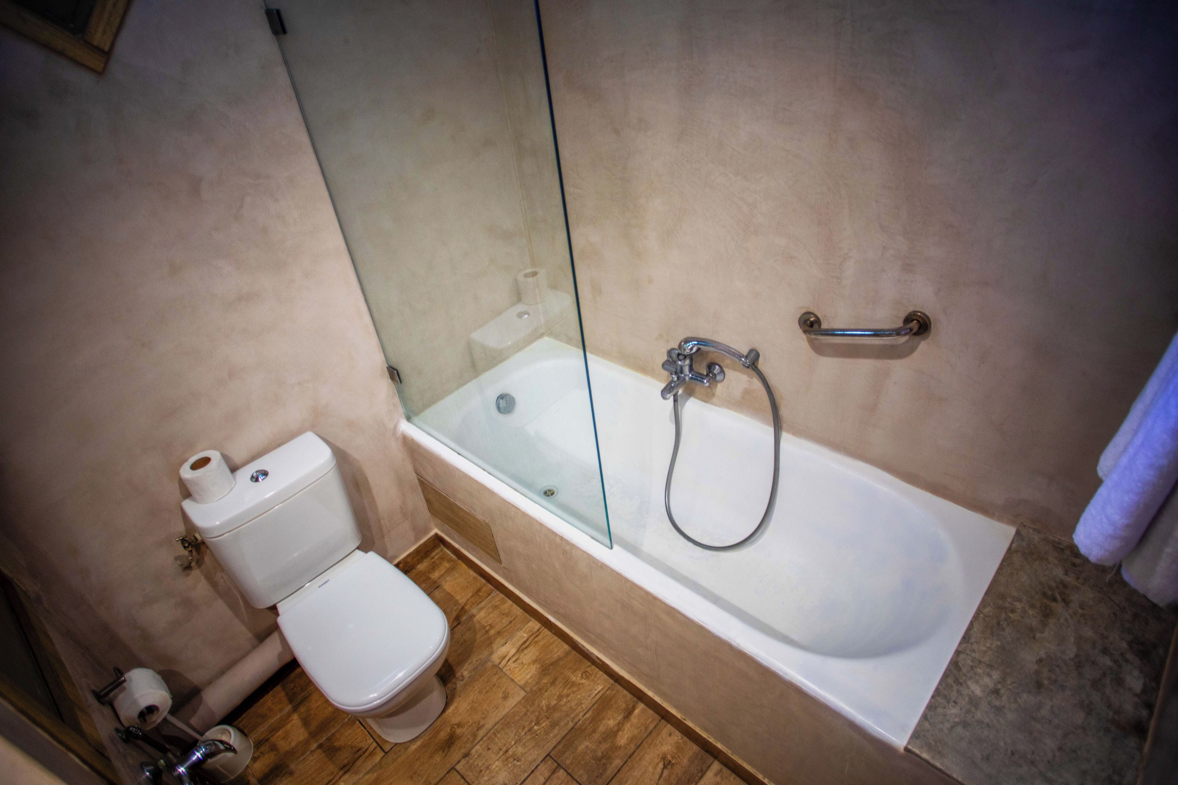 Un baño con inodoro, ducha con mampara de vidrio y bañera.