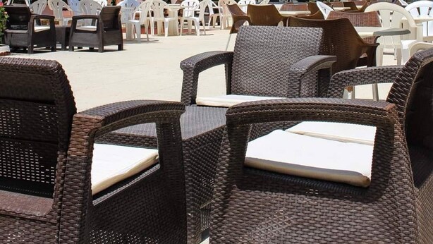A resort with outdoor seating, palm trees, and a white building with balconies. - Hotel Emira (Hammamet)