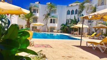 Een binnenzwembad, een buitenzwembad en parasols bij het zwembad