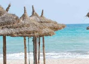 Una platja amb sombrerets de palla i una vista clara de l'oceà.