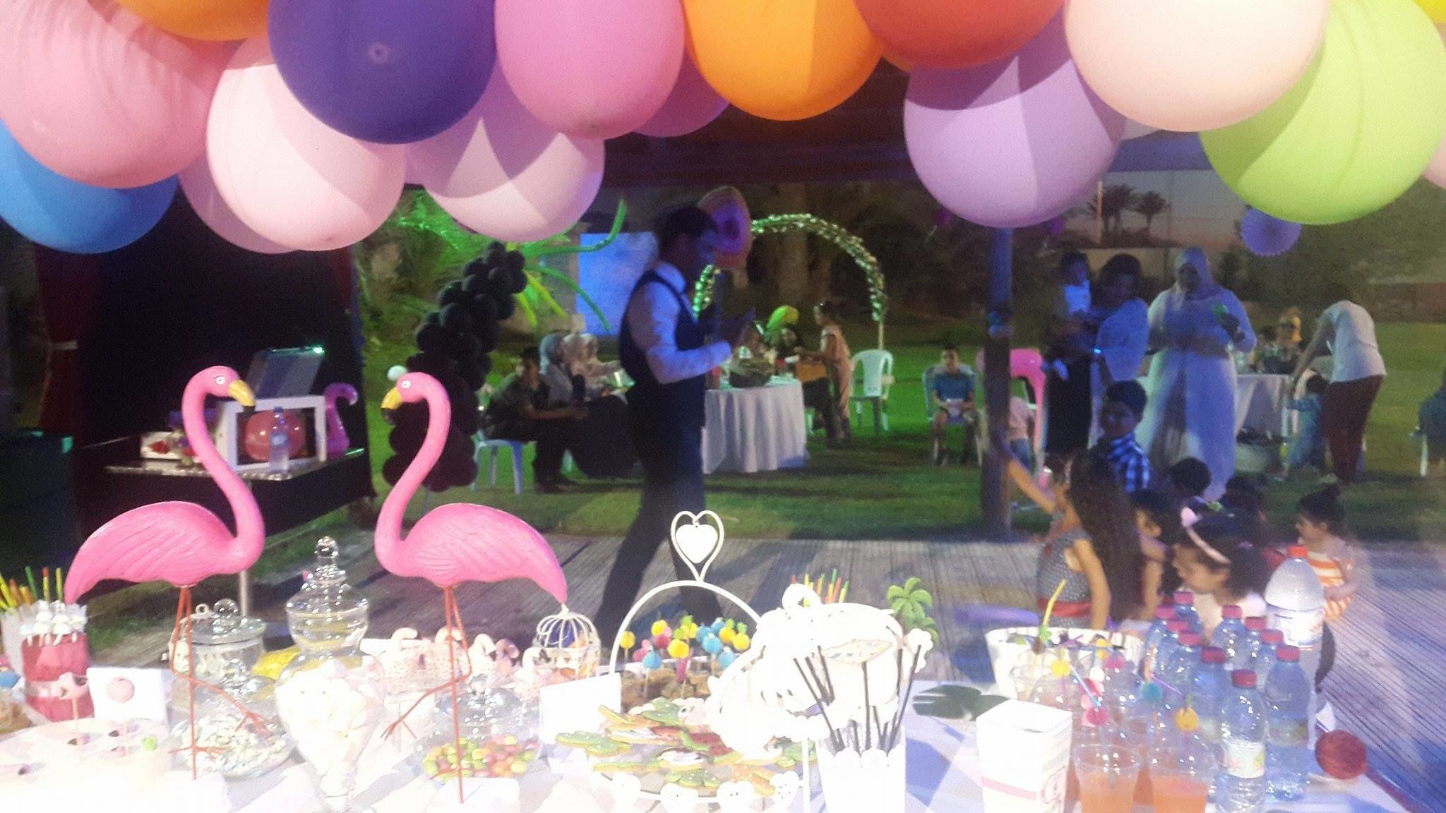 A decorated outdoor event with tables, balloons, and a flamingo decoration.