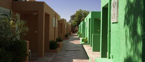 Un callejón estrecho flanqueado por edificios, uno pintado en un beige cálido y el otro en verde brillante.