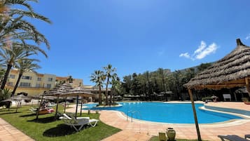 Relax by the pool surrounded by lush greenery and comfortable lounge chairs.