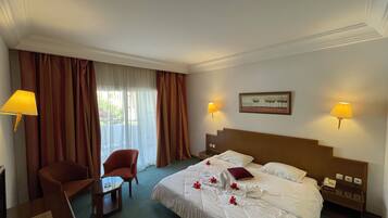 Habitación de hotel con cama, dos sillas, una mesa, una lámpara y un cuadro en la pared.
