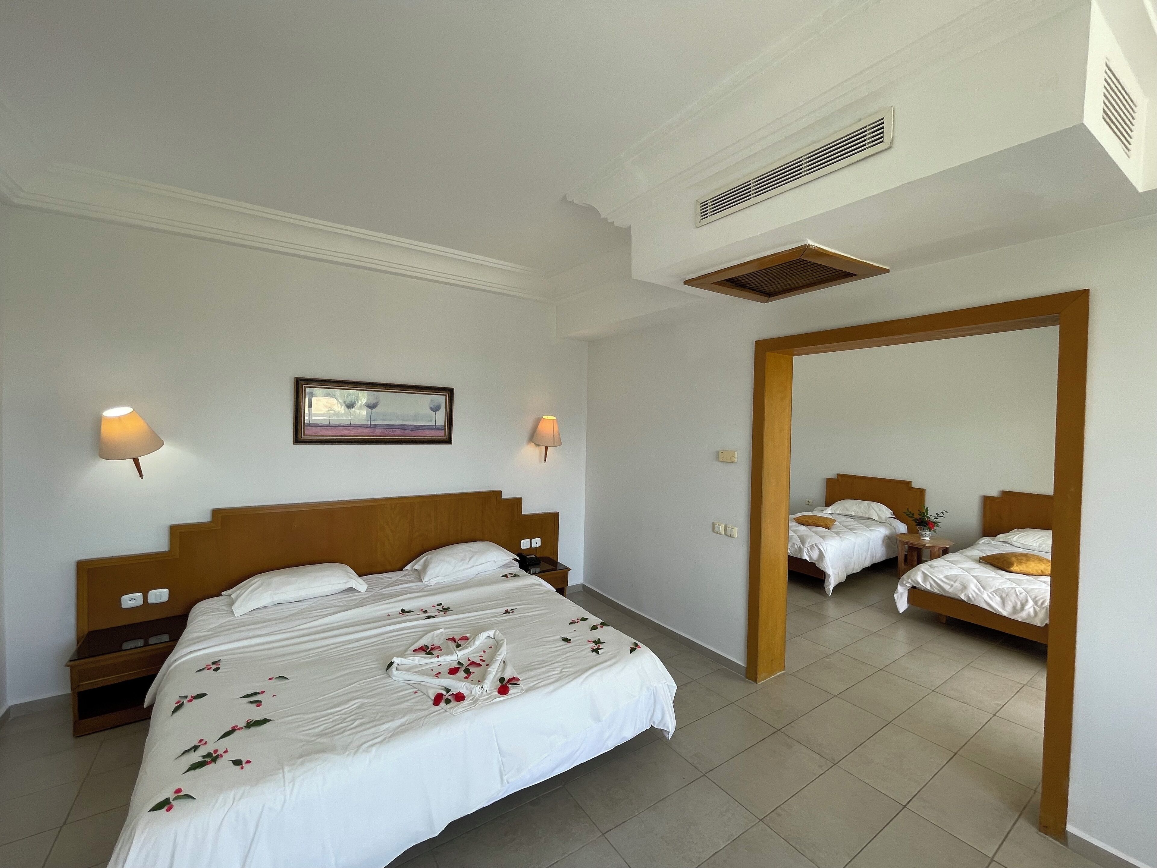 A hotel room with a large bed, two bedside tables, a mirror, and a picture on the wall.
