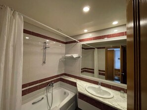 Une salle de bain avec une baignoire, un lavabo et un miroir.