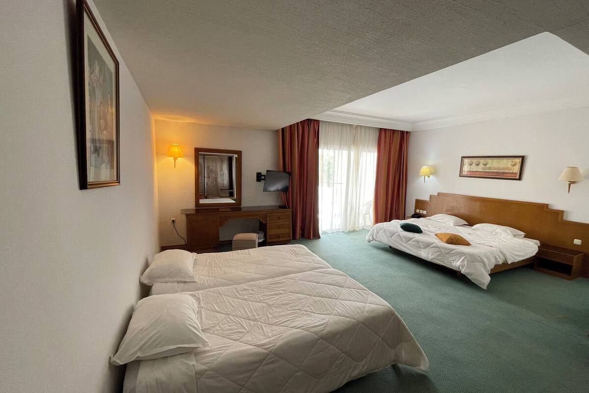 Ein Hotelzimmer mit zwei Betten, einem Schreibtisch, einem Stuhl und einem Fernseher.
