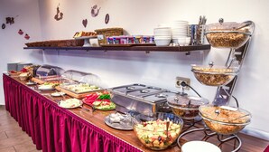 A buffet setup with various food items, including fruits, cereals, and dairy products, arranged on a long table with a red tablecloth. - Hotel Himalaya Frankfurt City Messe (Frankfurt)
