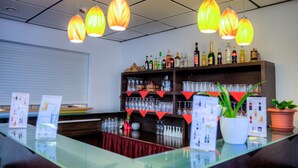 A bar area with hanging lamps, shelves of bottles, and a glass display. - Hotel Himalaya Frankfurt City Messe (Frankfurt)