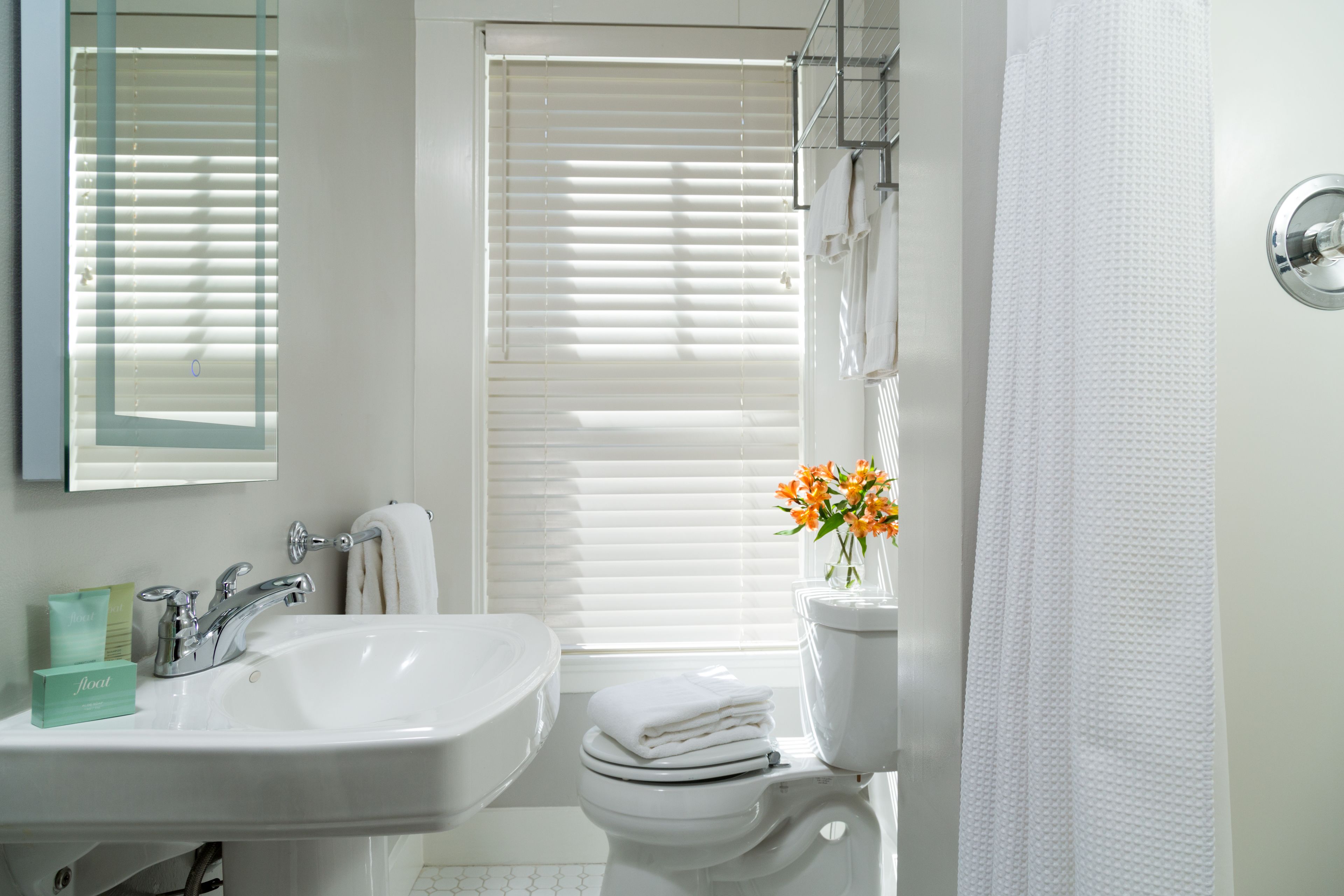 A bathroom with a white sink, toilet, and shower curtain.
