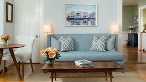 A living room with a blue sofa, two patterned pillows, a wooden coffee table, and a framed picture on the wall. - Brass Lantern Inn (Nantucket)