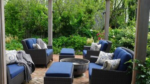 A covered patio area with wicker furniture and a central fire feature. - Brass Lantern Inn (Nantucket)