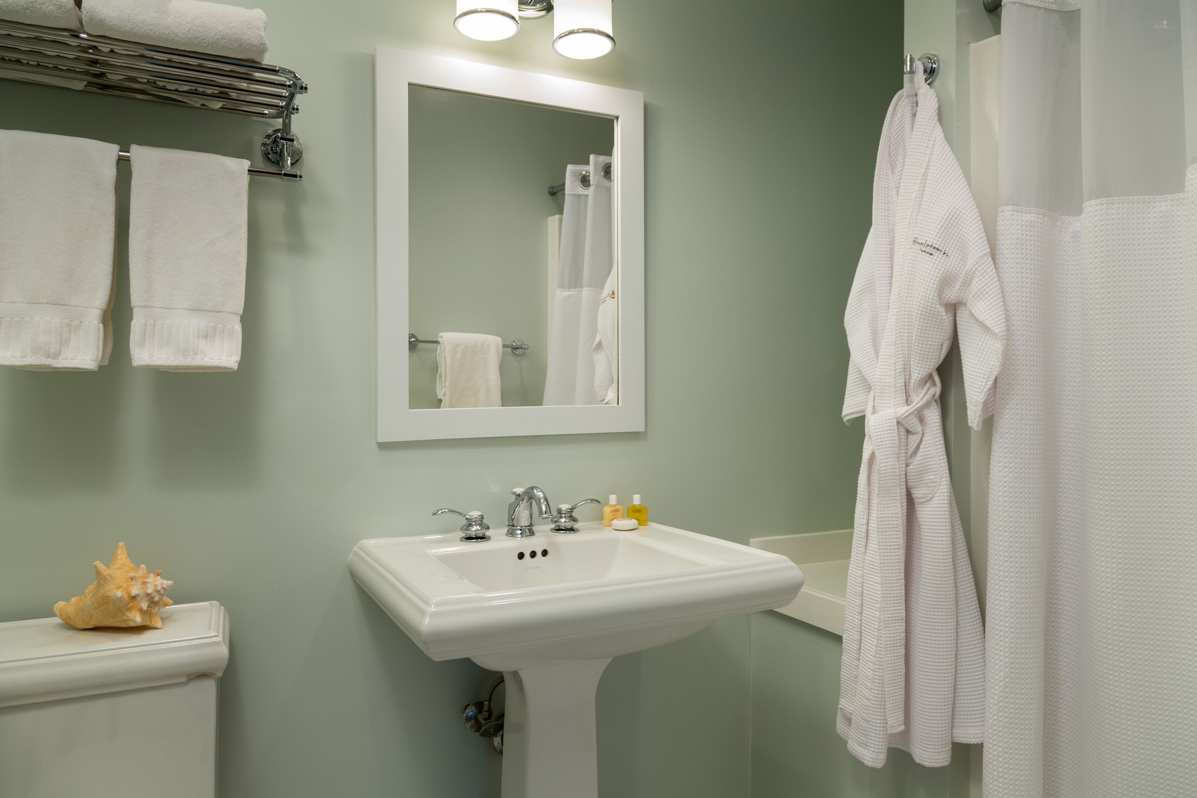A bathroom with a white sink, two towels on the wall, a mirror, and a shower curtain.