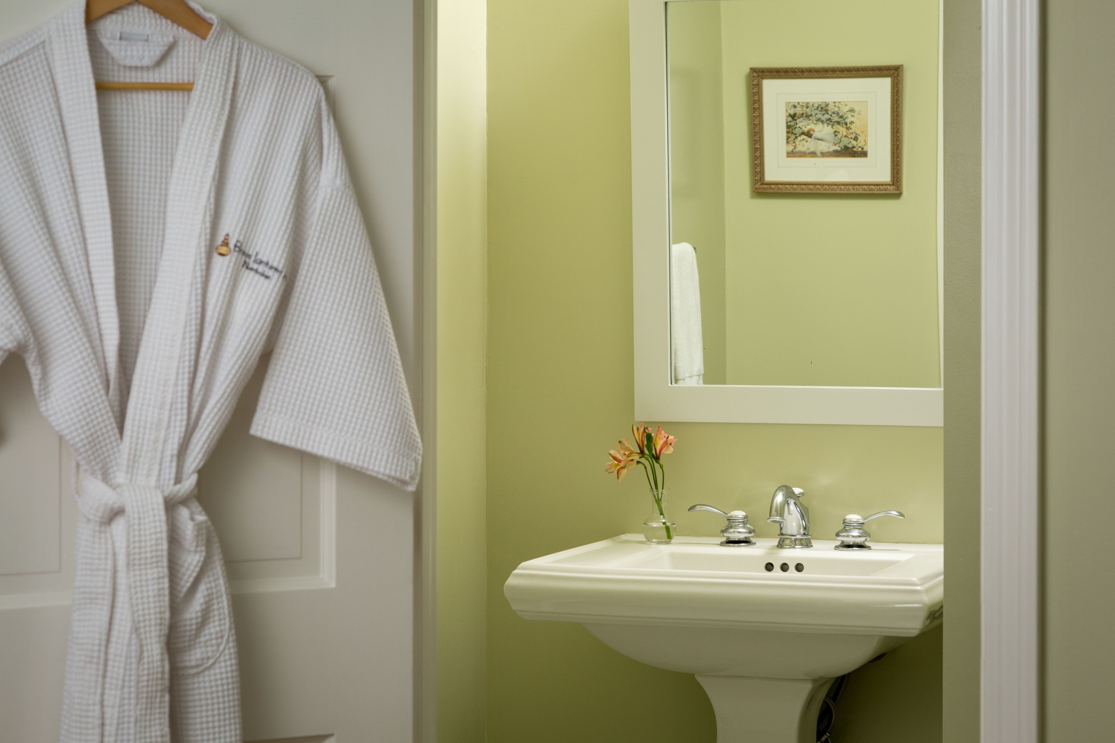 A bathroom with a white sink, a mirror, and a framed picture on the wall.