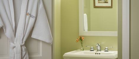 A bathroom with a white sink, a mirror, and a framed picture on the wall.