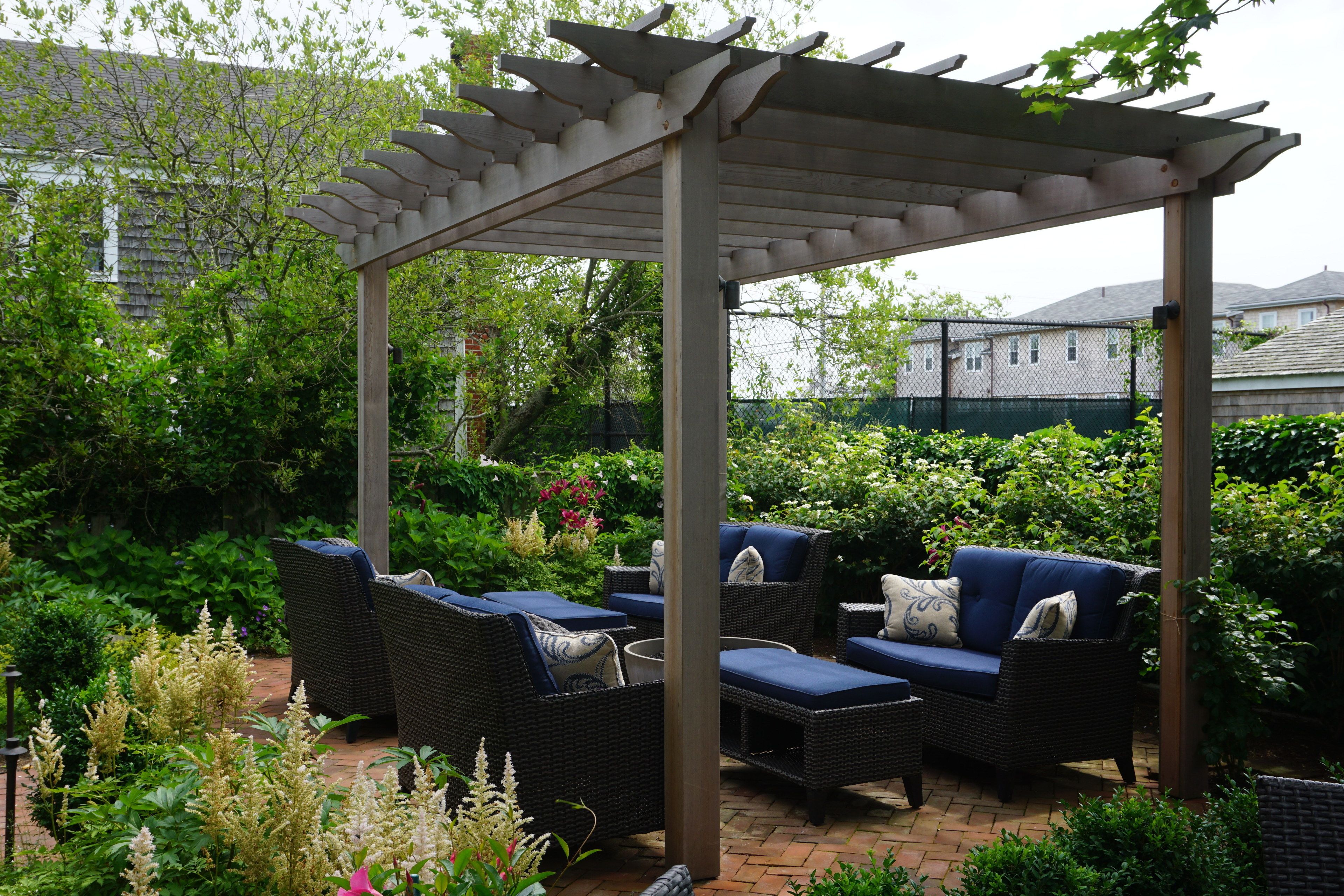 Un patio couvert aménagé avec des meubles en osier et une pergola.