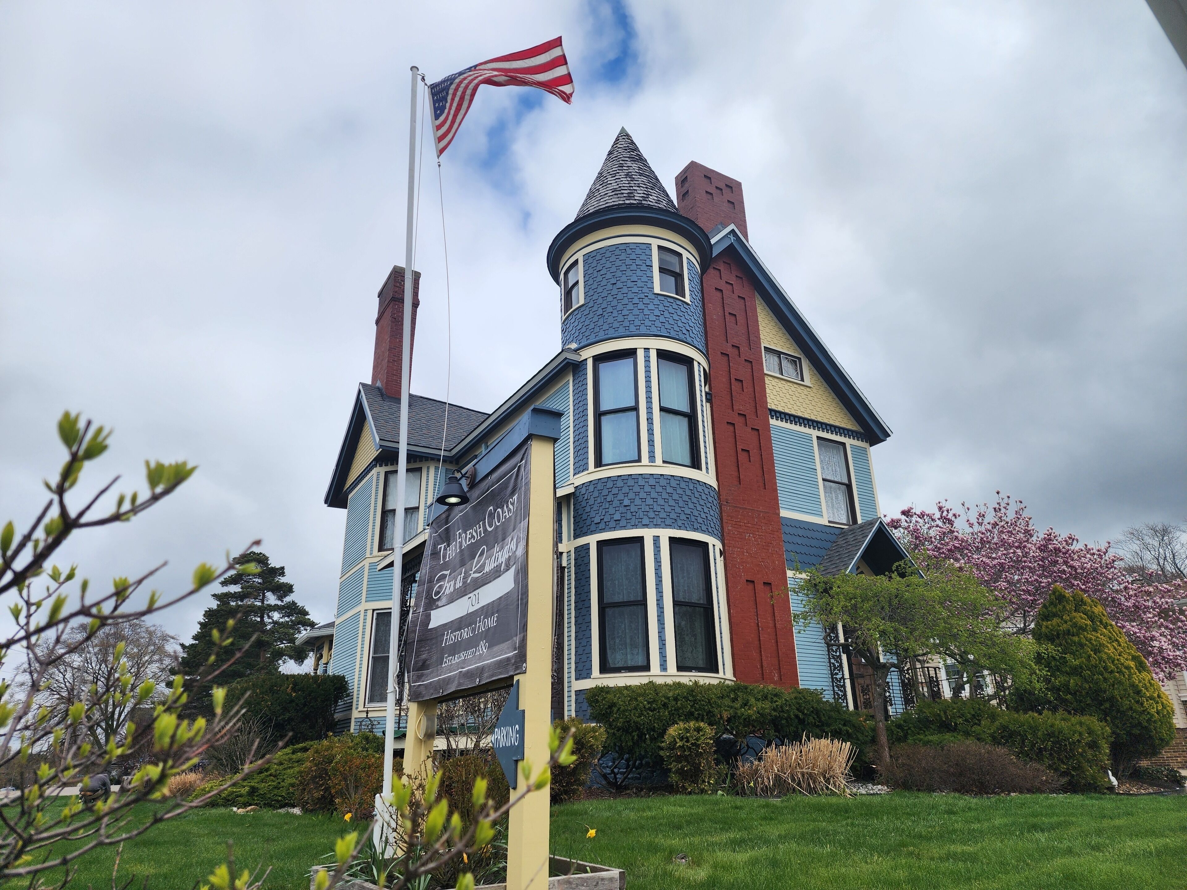 A historic home with a flagpole, a sign indicating it's a historic site, and a parking sign.