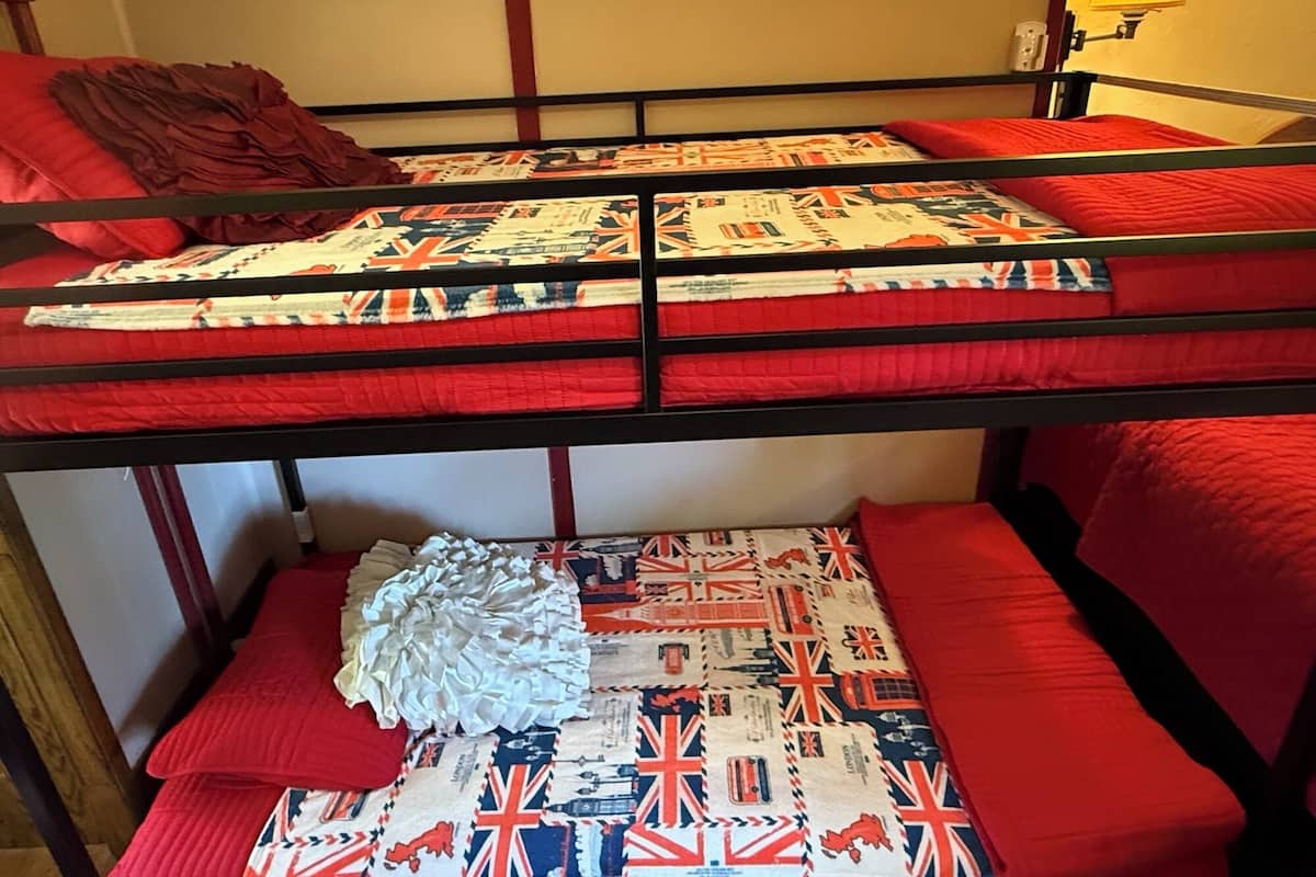 Un lit superposé avec une literie rouge et une courtepointe ornée de drapeaux britanniques.