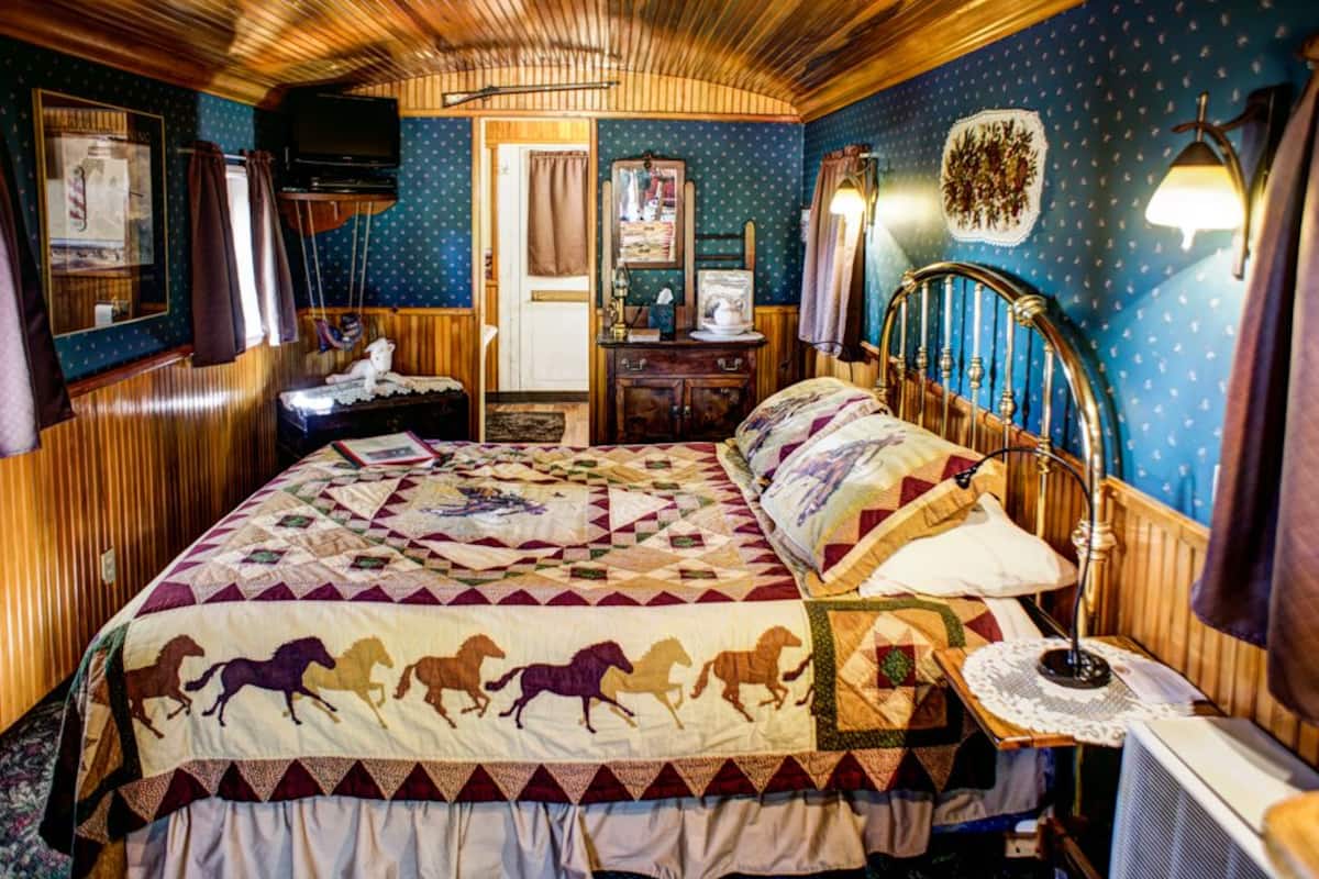 Une chambre avec un grand lit, une commode, un miroir et un téléviseur.