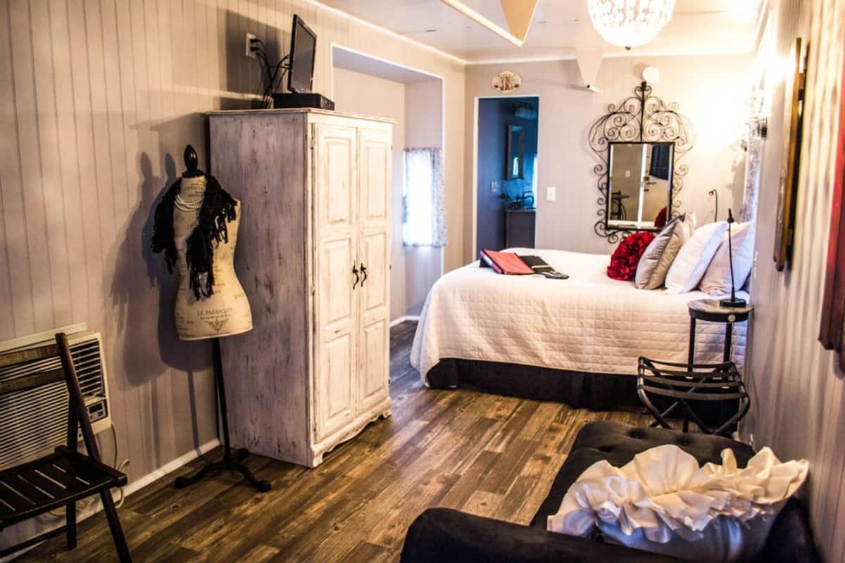 Une chambre à coucher avec un lit, une armoire, un miroir et une chaise.
