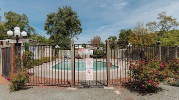 A gated pool area with a closed sign, a lifeguard warning sign, and a no glass allowed sign.