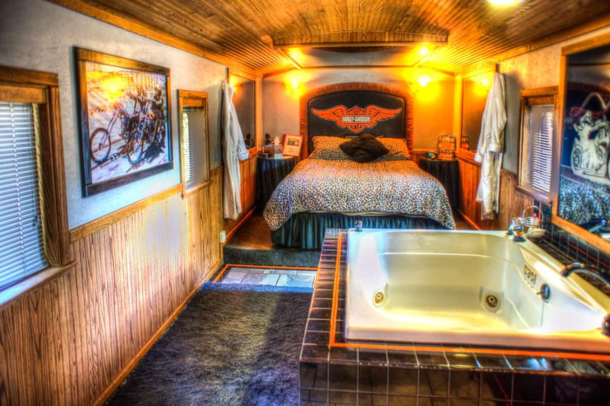Une chambre avec une tête de lit sur le thème de Harley-Davidson, une grande baignoire et un lambris en bois.