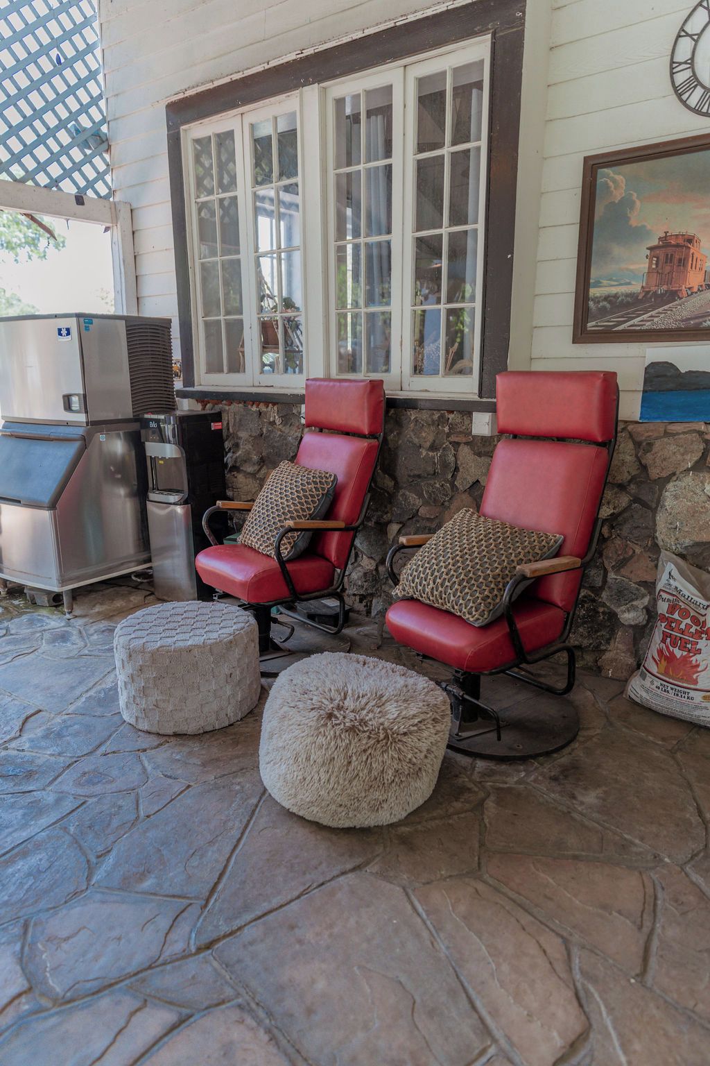 A patio area with two red chairs, a stone wall, and a grill.