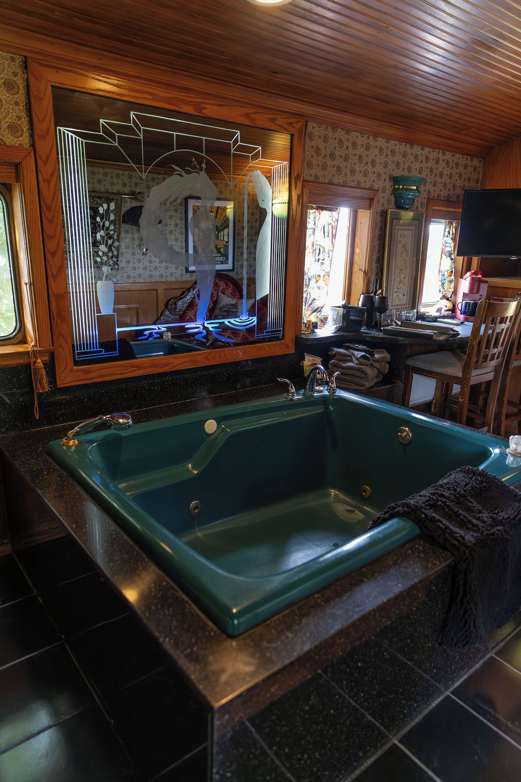 A bathroom with a large bathtub, a mirror, and a window.