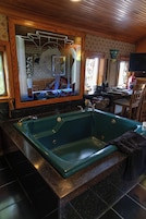 Un baño con una bañera grande, un espejo y una ventana.